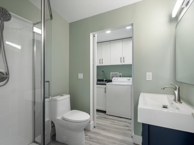 bathroom featuring an enclosed shower, toilet, washer and clothes dryer, vanity, and hardwood / wood-style flooring