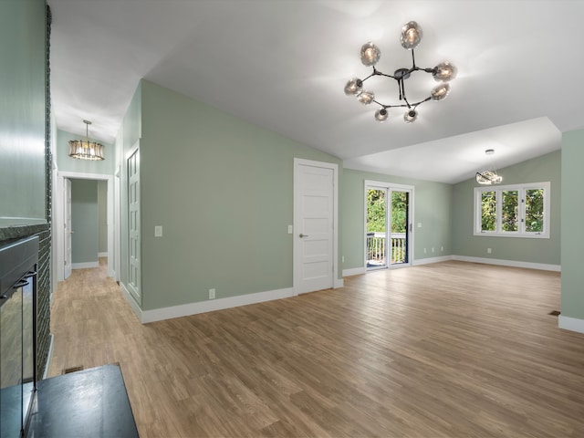 unfurnished living room featuring a notable chandelier, light wood-type flooring, and lofted ceiling