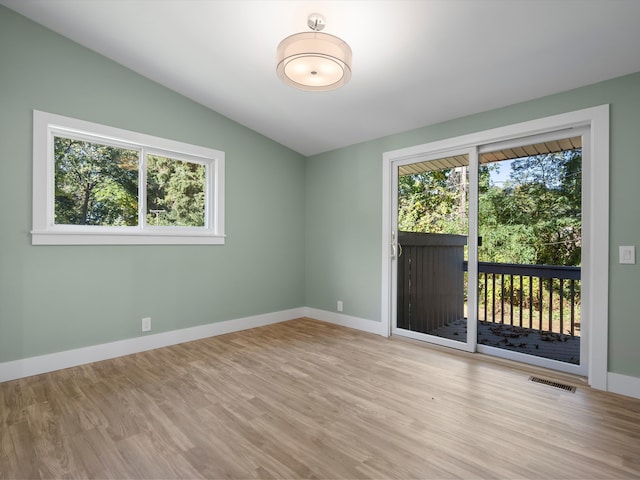 spare room featuring light hardwood / wood-style flooring and lofted ceiling