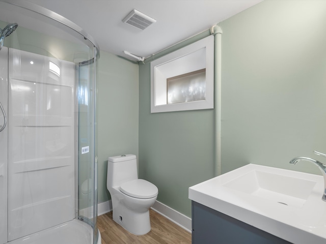 bathroom with toilet, hardwood / wood-style floors, vanity, and walk in shower