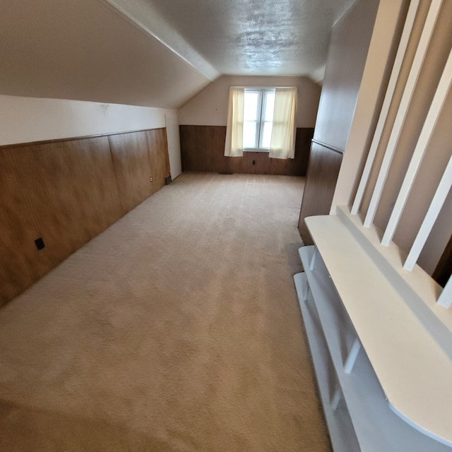 bonus room featuring light colored carpet, lofted ceiling, and wooden walls