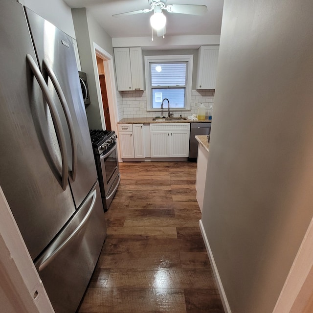 kitchen featuring backsplash, dark wood-type flooring, white cabinets, sink, and appliances with stainless steel finishes