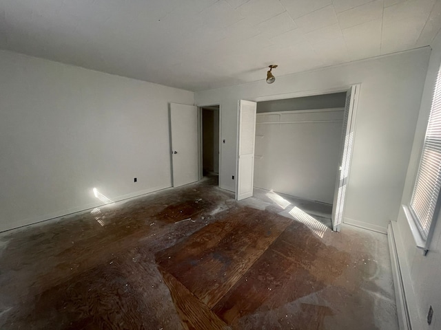 unfurnished bedroom featuring a closet and a baseboard heating unit