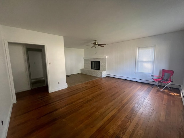 unfurnished living room with a fireplace, dark hardwood / wood-style floors, baseboard heating, and ceiling fan