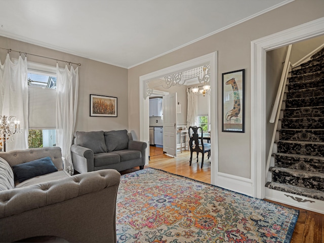 living room with light hardwood / wood-style flooring, ornamental molding, and a notable chandelier