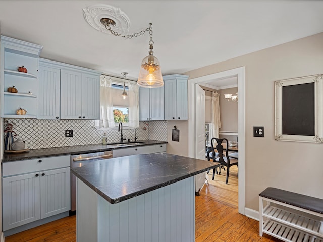 kitchen with decorative backsplash, light hardwood / wood-style floors, a kitchen island, and sink