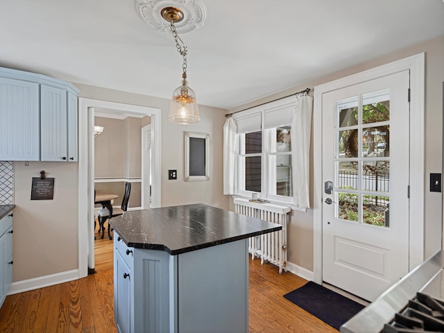 kitchen featuring radiator, a center island, hanging light fixtures, blue cabinets, and wood-type flooring