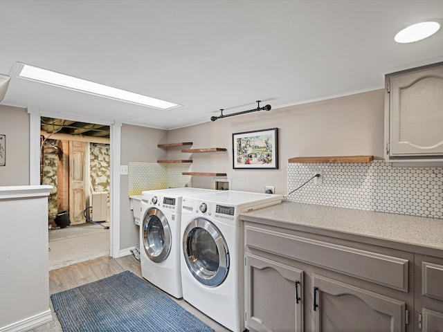 laundry area with washer and dryer, light hardwood / wood-style floors, and cabinets