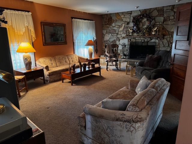 living room with carpet and a stone fireplace