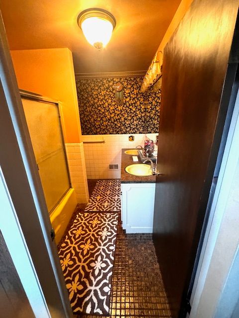 bathroom with crown molding, vanity, and tile walls