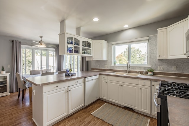 kitchen featuring kitchen peninsula, dark hardwood / wood-style flooring, sink, dishwasher, and white cabinets