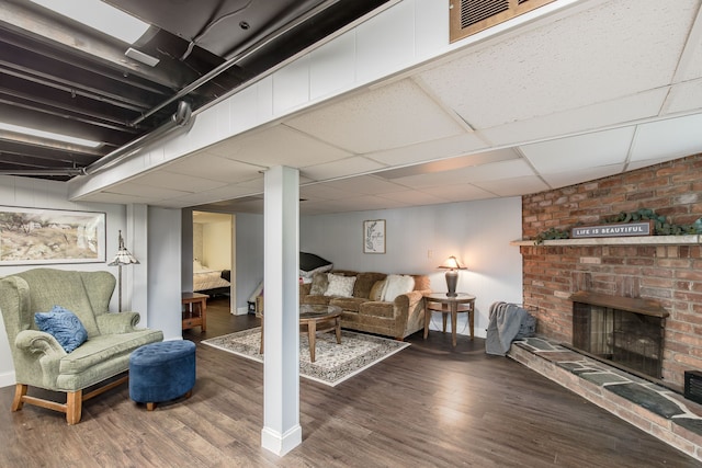 basement with a fireplace, a paneled ceiling, and hardwood / wood-style flooring