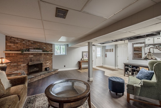 living room with a fireplace, hardwood / wood-style floors, and a drop ceiling