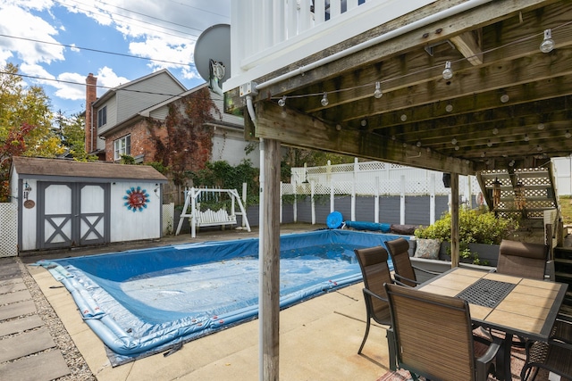 view of pool featuring a water view, a patio, and a storage unit