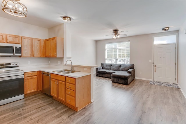 kitchen with ceiling fan, sink, kitchen peninsula, appliances with stainless steel finishes, and light wood-type flooring