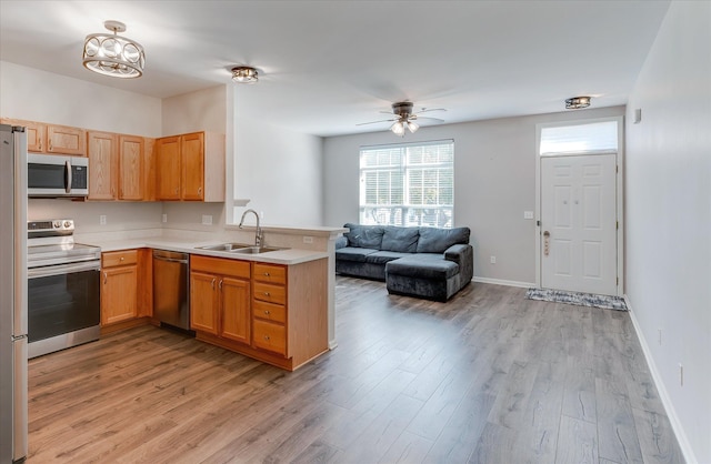 kitchen featuring ceiling fan, sink, stainless steel appliances, kitchen peninsula, and light hardwood / wood-style floors