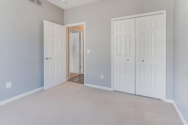 unfurnished bedroom with light carpet and a closet