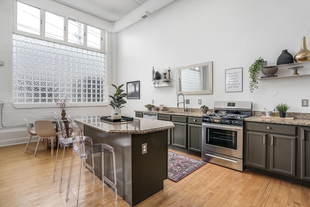 kitchen with sink, dark stone counters, stainless steel gas stove, and a center island