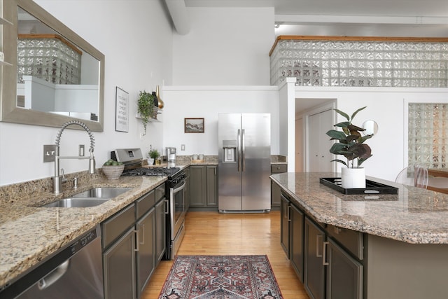 kitchen featuring sink, stainless steel appliances, light wood-type flooring, and light stone countertops