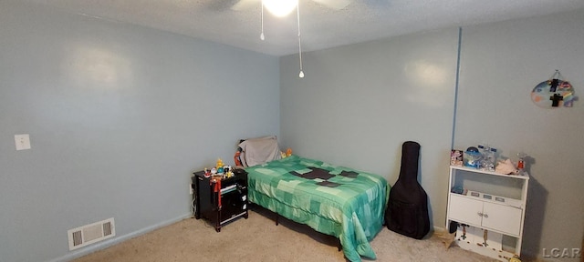 bedroom featuring ceiling fan, light colored carpet, and a textured ceiling