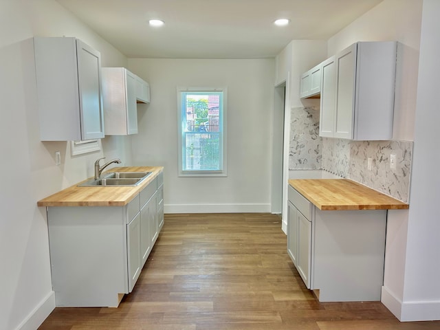 kitchen with butcher block countertops, white cabinets, and light wood-type flooring