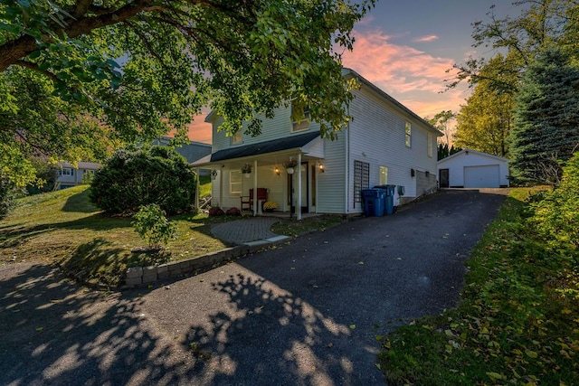 view of front of property featuring an outbuilding, a yard, a garage, and covered porch