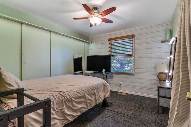 bedroom with carpet floors, a closet, ceiling fan, and wood walls