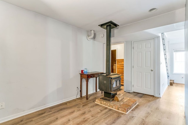 basement featuring light hardwood / wood-style floors and a wood stove