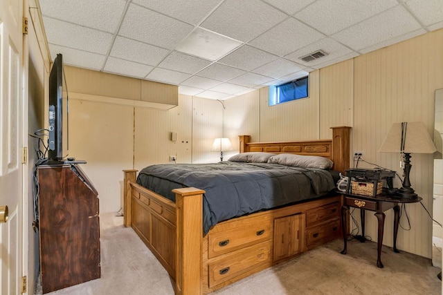 bedroom featuring light carpet and a drop ceiling