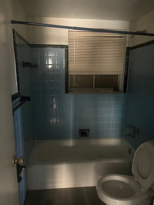 bathroom with toilet, wood-type flooring, and tiled shower / bath