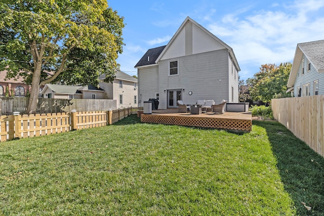 rear view of property with a lawn, central AC unit, and a wooden deck