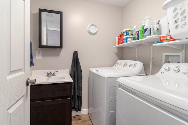 laundry area featuring cabinets, hardwood / wood-style floors, separate washer and dryer, and sink