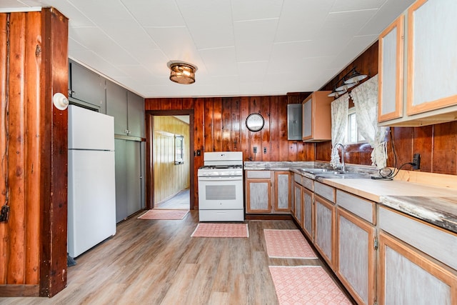 kitchen with sink, white appliances, light hardwood / wood-style flooring, and wood walls