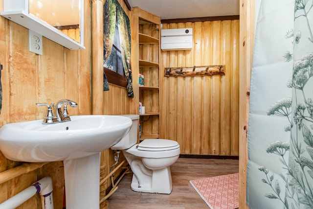 bathroom featuring wood walls, toilet, wood-type flooring, and a shower