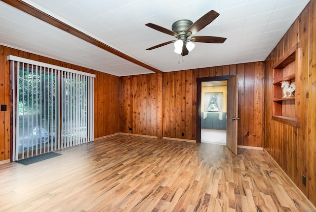 spare room with wood walls, ceiling fan, and light hardwood / wood-style floors