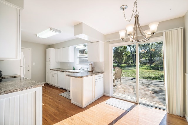 kitchen with white cabinetry, dishwasher, an inviting chandelier, decorative light fixtures, and light wood-type flooring