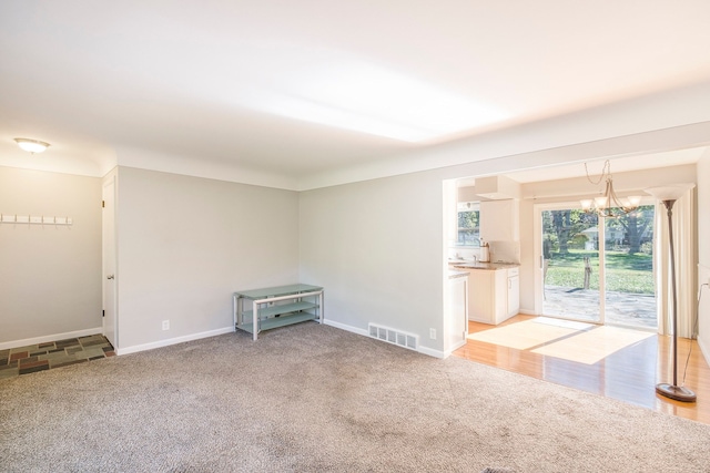 carpeted spare room with an inviting chandelier