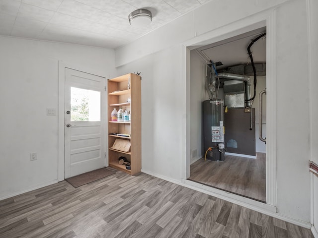 foyer entrance with vaulted ceiling, gas water heater, and light hardwood / wood-style flooring