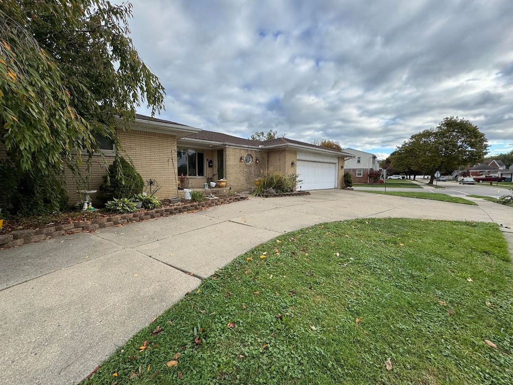 single story home with a front lawn, brick siding, a garage, and driveway