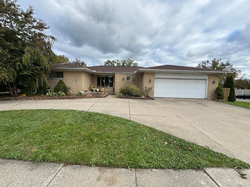 ranch-style house with a front lawn, brick siding, a garage, and driveway