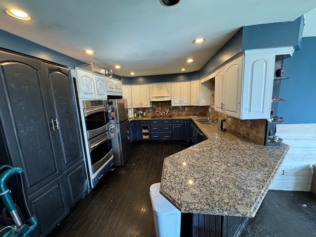 kitchen with stainless steel refrigerator, white cabinetry, stone counters, and tasteful backsplash