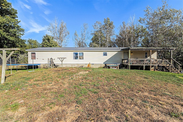 back of house featuring a yard, a deck, and a trampoline