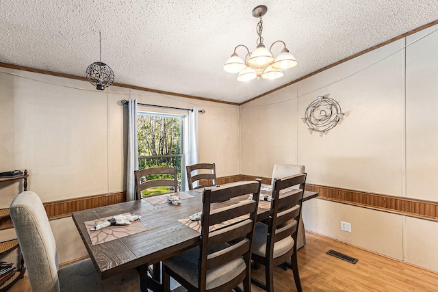 dining space with hardwood / wood-style floors, ornamental molding, a textured ceiling, and a notable chandelier