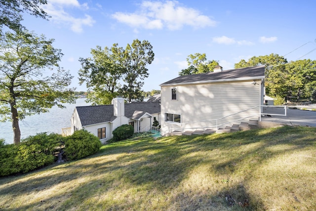 view of home's exterior with a water view and a yard