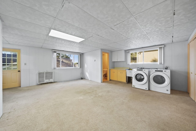 laundry area with heating unit, light carpet, cabinets, and independent washer and dryer