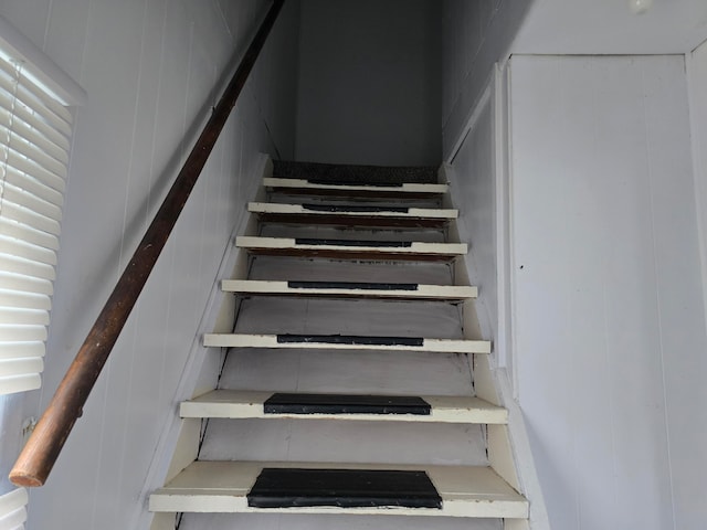 stairway featuring wooden walls