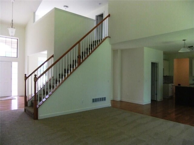 48945 Tuscan Hls, Plymouth, MI 48170 - unfurnished living room featuring carpet floors, a towering ceiling, stairway, a chandelier, and baseboards