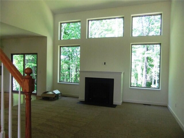 48945 Tuscan Hls, Plymouth, MI 48170 - unfurnished living room with carpet, healthy amount of natural light, a high ceiling, stairway, and a fireplace with flush hearth