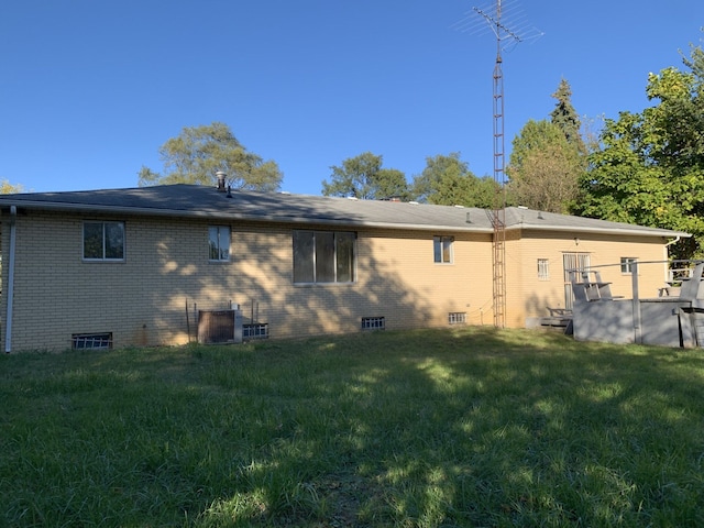 rear view of house featuring a lawn and central AC unit