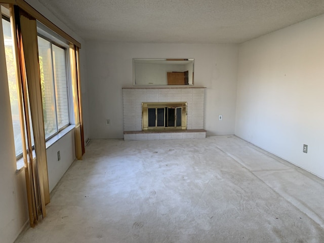 unfurnished living room with a textured ceiling and a tiled fireplace